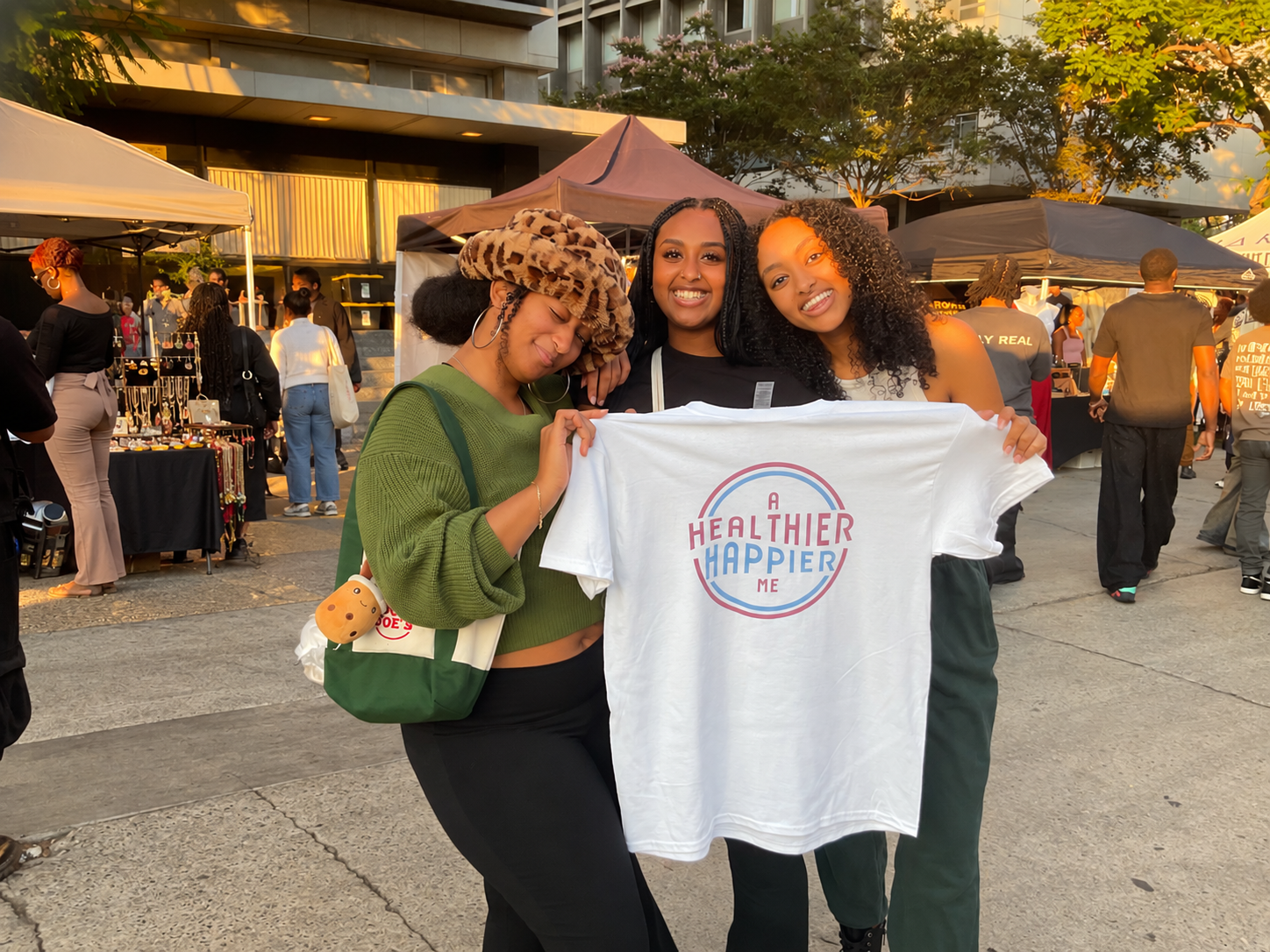 Three students holding an A Healthier Happier Me t-shirt